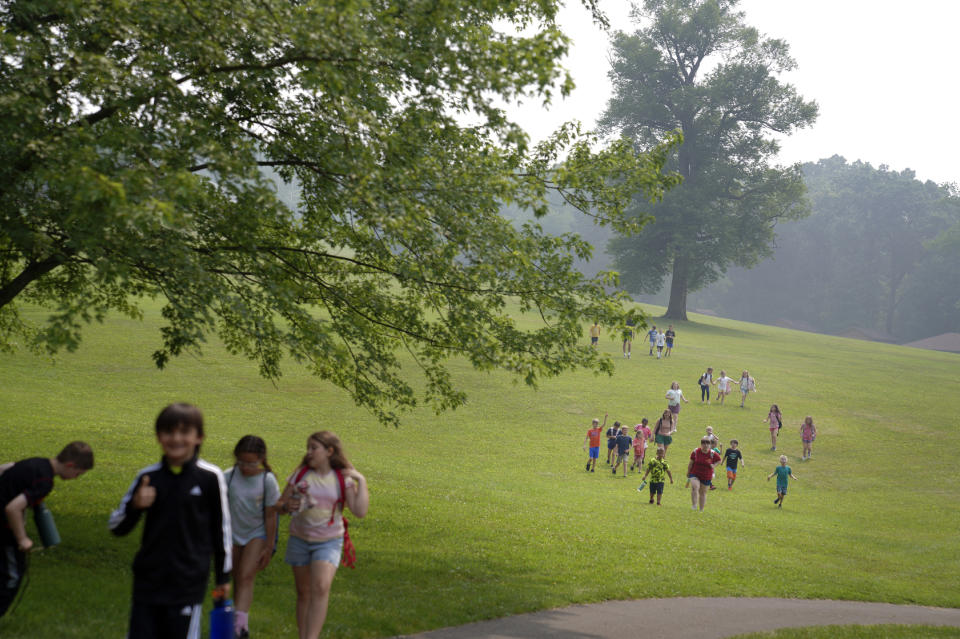 Kids walk across the YMCA Camp Kon-O-Kwee Spencer campground through smokey haze to their next indoor activity, in Zelienople, Pa., on Thursday, June 29, 2023. Due to the poor air quality caused by the Canadian wildfires the Western Pennsylvania summer camp closed its outdoor pool and sent home a few campers with health problems. (AP Photo/Jessie Wardarski)
