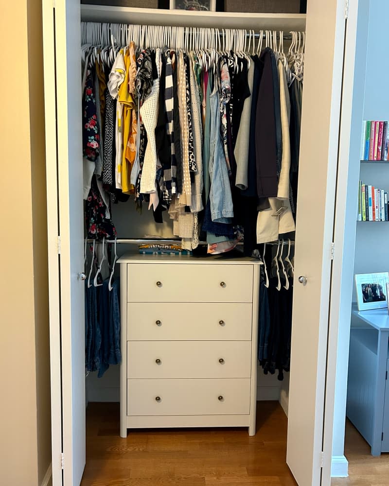 Clothes hanging in closet of studio apartment.