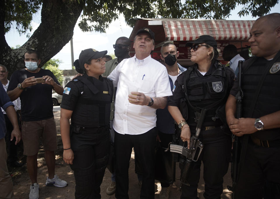 Brazil's President Jair Bolsonaro, center, talks with police officers after voting during the run-off municipal elections in Rio de Janeiro, Brazil, Sunday, Nov. 29, 2020. Bolsonaro, who sometimes has embraced the label "Trump of the Tropics," said Sunday he'll wait a little longer before recognizing the U.S. election victory of Joe Biden, while also echoing President Donald Trump's allegations of irregularities in the U.S. vote. (AP Photo/Silvia Izquierdo)