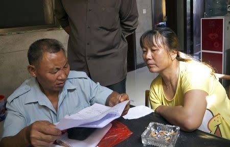 Farmer Li Laiyin (L), 64, and his neighbours look through a list of local residents with elevated levels of lead in their blood, in Dapu, Hunan province, June 25, 2014. REUTERS/Alexandra Harney