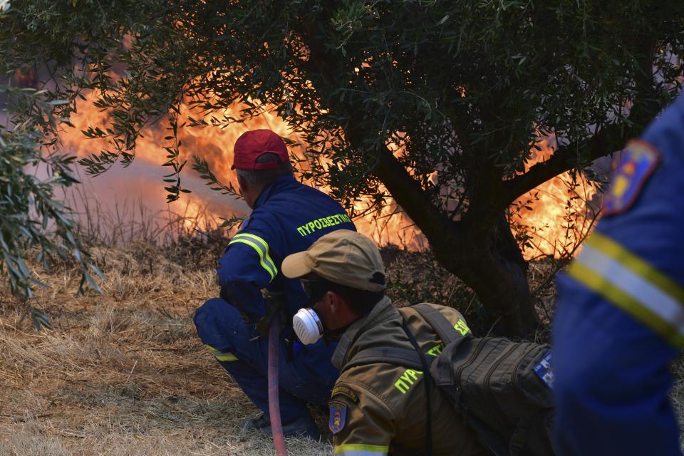 Firefighters try to extinguish a wildfire near Olympia town, western Greece, Thursday, Aug. 5, 2021. Wildfires rekindled outside Athens and forced more evacuations around southern Greece Thursday as weather conditions worsened and firefighters in a round-the-clock battle stopped the flames just outside the birthplace of the ancient Olympics. (Giannis Spyrounis/ilialive.gr via AP)