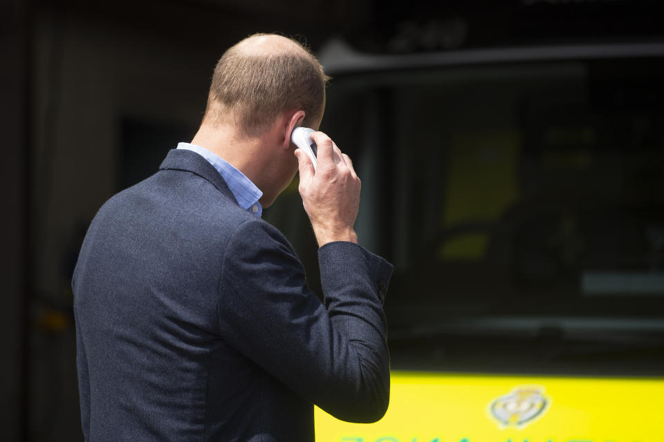 The Duke of Cambridge places a thermometer in his ear to check his temperature as he arrives at the Ambulance Station in King's Lynn, Norfolk, to meet staff from the England Ambulance Service Trust.