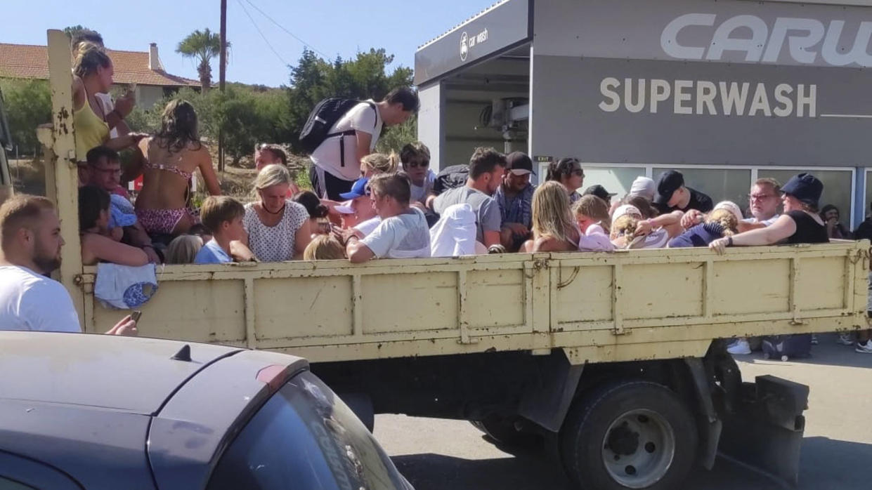 Des touristes assis à l’arrière d’un camion alors qu’ils sont évacués lors d’incendies sur l’île de Rhodes le 22 juillet 2023. 