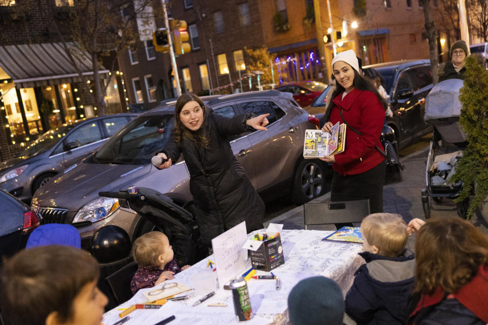 Rabbanit Dasi Fruchter, of the South Philadelphia Shtiebel, reads to children during a public Hanukkah celebration and menorah lighting ceremony in South Philadelphia on Sunday, Dec. 5, 2021. Fruchter is one of about a half-dozen ordained women who serve at Modern Orthodox synagogues across the U.S. and one of even fewer who serve as top spiritual leaders. (AP Photo/Ryan Collerd)