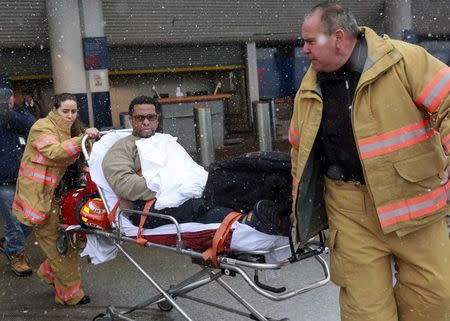 A passenger is wheeled on a stretcher through snowfall by emergency medical services workers at LaGuardia Airport's Terminal D in New York March 5, 2015. REUTERS/Shannon Stapleton