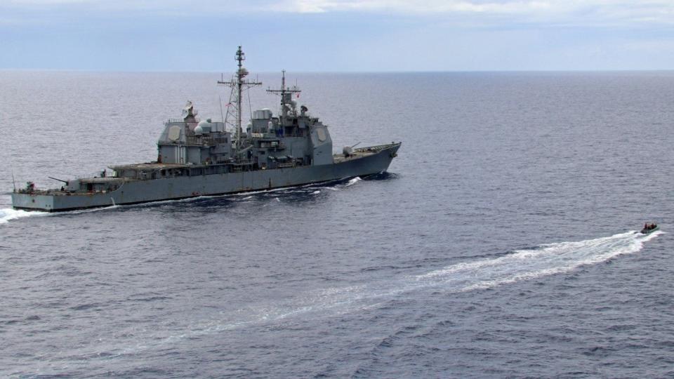 A small boat sails near guided-missile cruiser USS Leyte Gulf