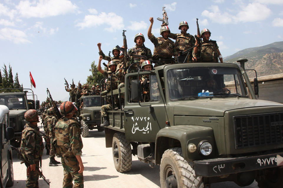 FILE - In this Friday, June 10, 2011 file photo taken during a government-organised visit for media, Syrian army soldiers standing on their military trucks shout slogans in support of Syrian President Bashar Assad, as they enter a village near the town of Jisr al-Shughour, north of Damascus, Syria. Nearly three years after the crisis began, Syria's government and opposition are set to meet in Geneva this week for the first direct talks aimed at ending the conflict. With stakes high and expectations low, Syria's government and its opponents sit down face-to-face at an international peace conference this week for the first time _ muscled to the negotiating table by foreign powers that fear the bloodiest of the Arab Spring uprisings may engulf the entire region in sectarian war. (AP Photo/Bassem Tellawi, File)