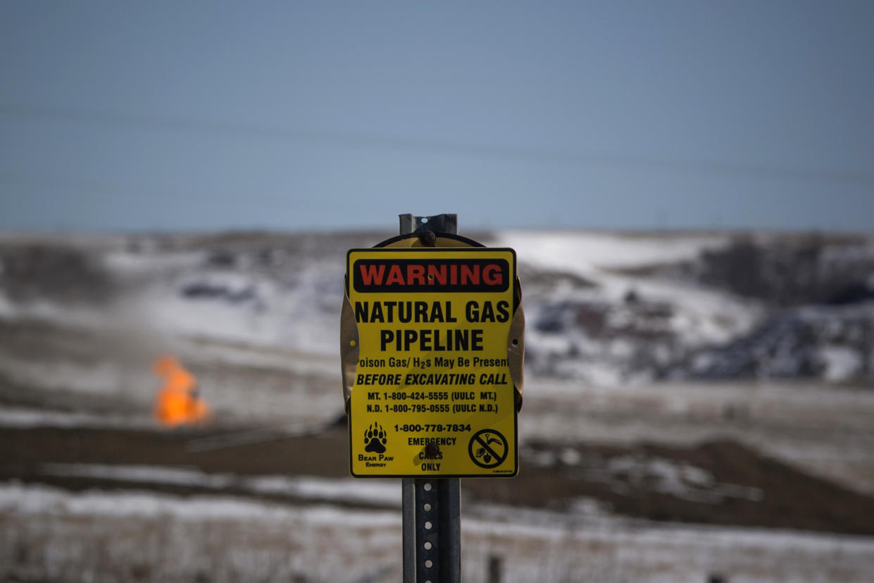 A warning sign for a natural gas pipeline is seen as natural gas flares at an oil pump site outside of Williston, North Dakota March 11, 2013. North Dakota's booming oil business has quickly ran up against a serious shortage of housing for the thousands of workers who have poured into the state looking to cash in on the Bakken oil formation that has made North Dakota the second-largest oil-producing state after Texas. Picture taken March 11, 2013.  REUTERS/Shannon Stapleton (UNITED STATES - Tags: BUSINESS ENERGY ENVIRONMENT COMMODITIES)