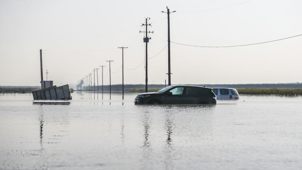 Two cars are stranded in the flood along a highway