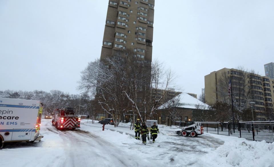 Minneapolis firefighters leave after a deadly fire at a high-rise apartment building, center in background, Wednesday, Nov. 27, 2019, in Minneapolis. (David Joles/Star Tribune via AP)