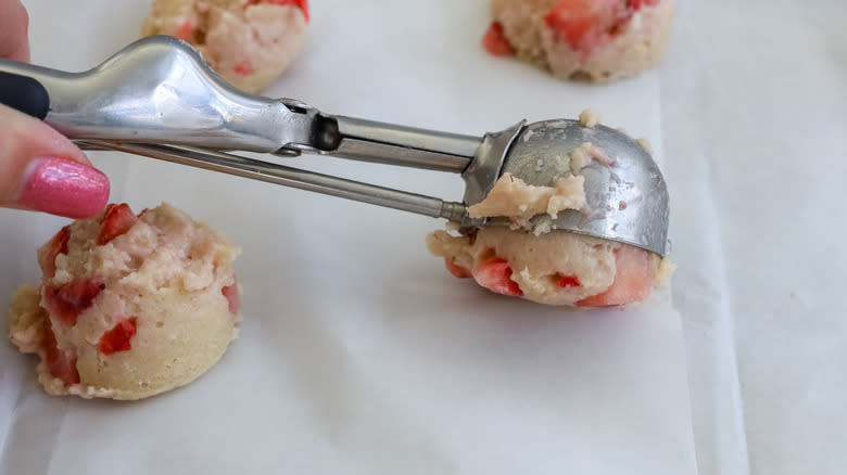 cookie dough being scooped onto baking pans