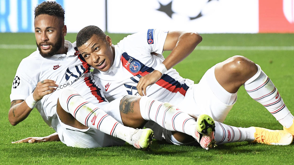 Kylian Mbappe (R) and forward Neymar hug and slide after a PSG goal.