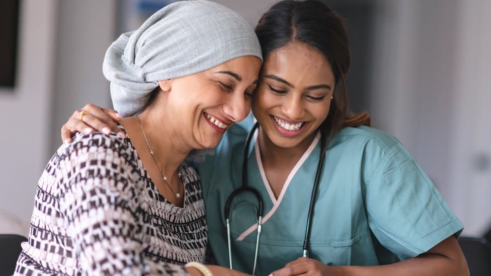 Una enfermera abraza a una paciente con cáncer.