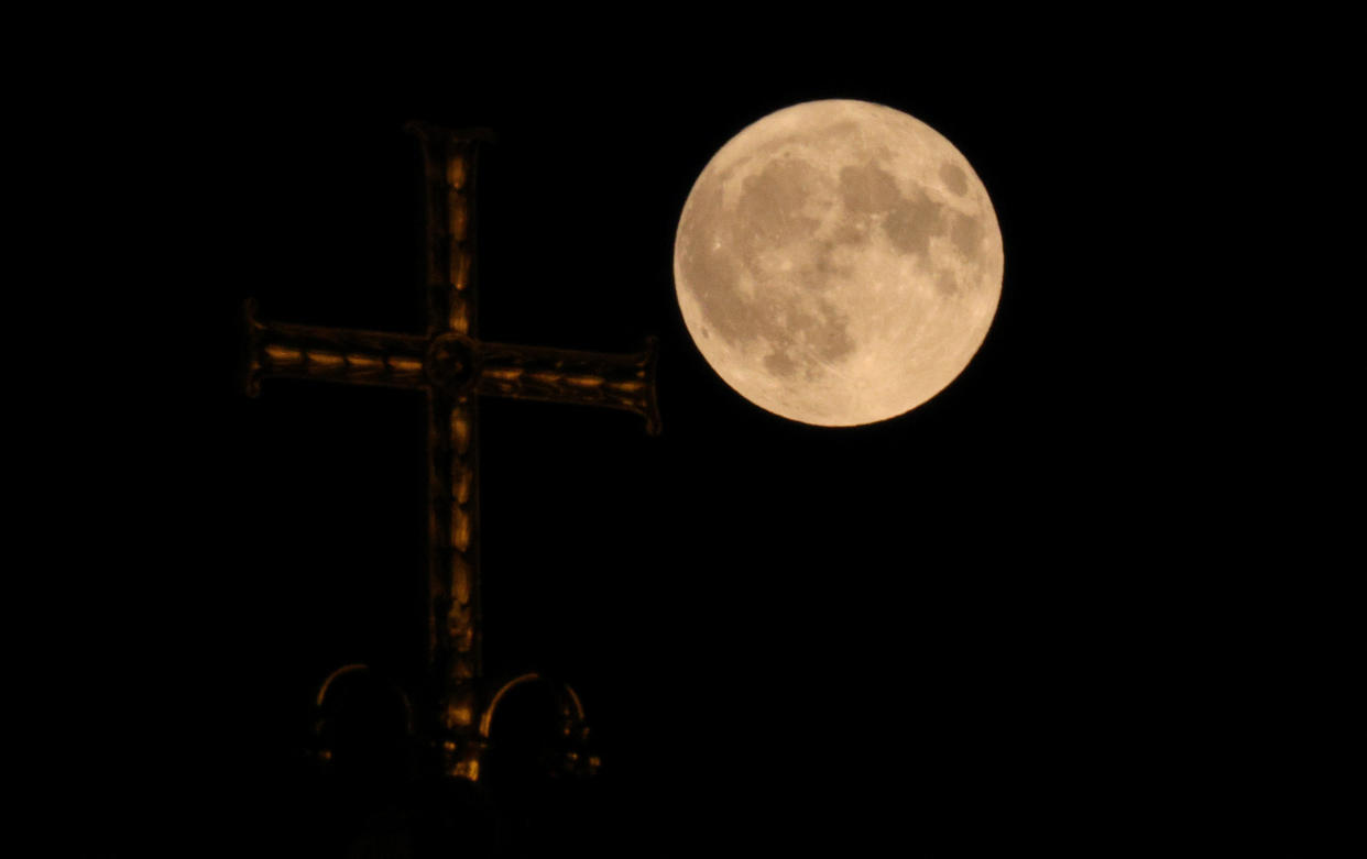 A dimly lit cross at Alexander Nevsky Cathedral in Sofia, Bulgaria, can be seen as the supermoon rises.