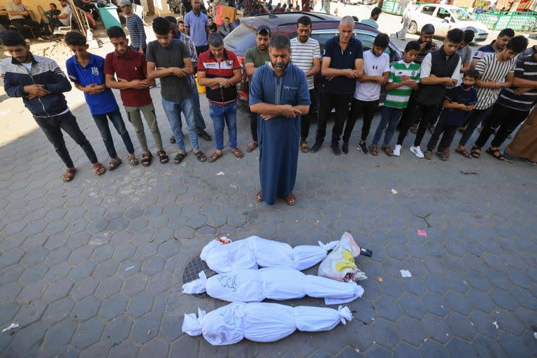 Los palestinos rezan junto a los cuerpos de los miembros de la familia al-Sarsak asesinados tras el bombardeo israelí, antes de trasladarlos para enterrarlos frente al Hospital de los Mártires de Al Aqsa en Deir al-Balah, en la zona central de la Franja de Gaza, el 30 de octubre de 2023, en medio de batallas en curso entre Israel y el grupo palestino Hamás. 
