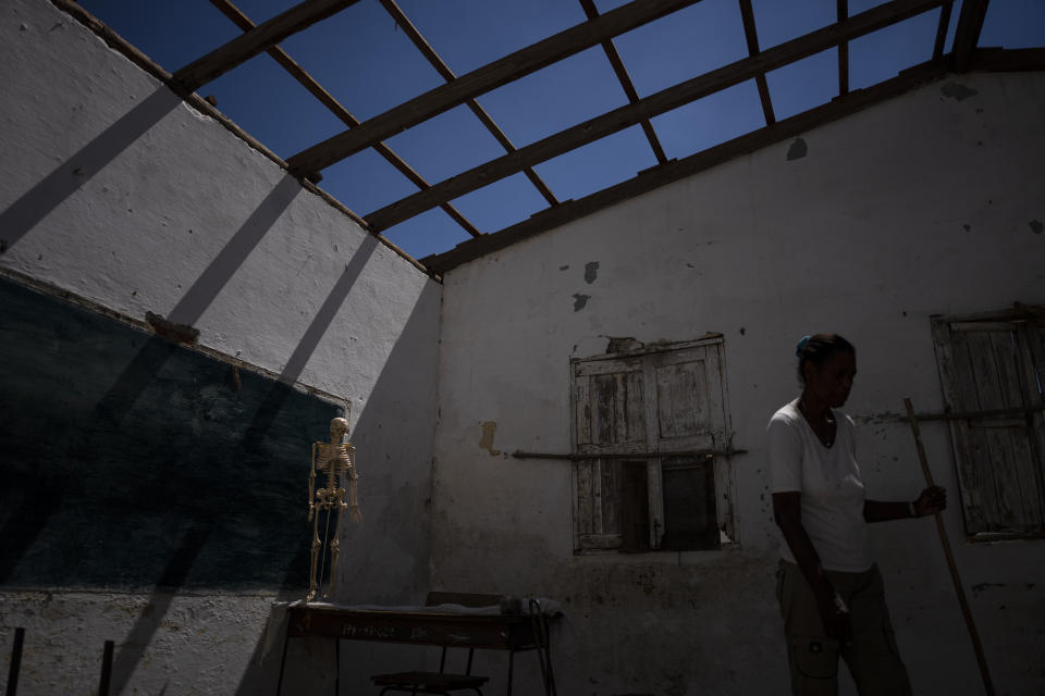 A volunteer cleans a roofless classroom at a school that was heavily damaged by Hurricane Ian in La Coloma, in the province of Pinar del Rio, Cuba, Wednesday, Oct. 5, 2022. (AP Photo/Ramon Espinosa)