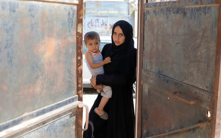 A woman holds her child as she is about to enter the school in Hazema North Raqqa, Syria August 21, 2017. REUTERS/Zohra Bensemra