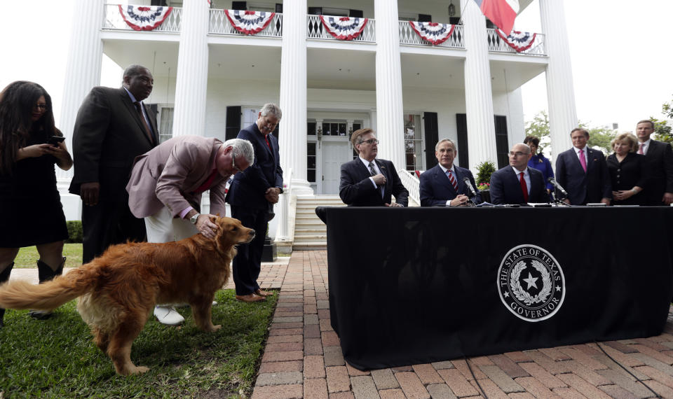 Governor Greg Abbott's dog Pancake joins Abbott, seated center, Lt. Governor Dan Patrick, seated left, and Speaker of the House Dennis Bonnen, seated right, and other law makers for a joint press conference where changes to teacher pay and school finance were announced at the Texas Governor's Mansion in Austin, Texas, Thursday, May 23, 2019, in Austin. (AP Photo/Eric Gay)