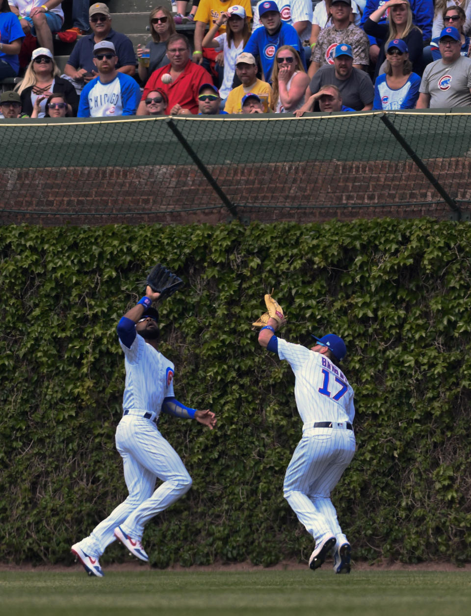 Chicago Cubs center fielder Jason Heyward, left, and right fielder Kris Bryant (17) both eye the ball before colliding while chasing a ball hit by Cincinnati Reds'c Eugenio Suarez (7) during the sixth inning of a baseball game Sunday, May 26, 2019, in Chicago. Bryant was charged with an error on the play. (AP Photo/Matt Marton)