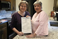 Mary Bishop-Baldwin, left, and Sharon Bishop-Baldwin, right, pose for a photo with their marriage license in their home Tuesday, Nov. 29, 2022, in Broken Arrow, Okla. (AP Photo/Sue Ogrocki)