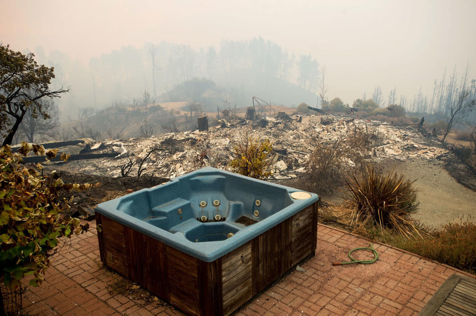 <p>A hot tub rests in front of a residence leveled by the Loma fire along Loma Chiquita Road on Tuesday, Sept. 27, 2016, near Morgan Hill, Calif. More California residents were ordered from their homes Tuesday as a growing wildfire threatened remote communities in the Santa Cruz Mountains. (AP Photo/Noah Berger) </p>