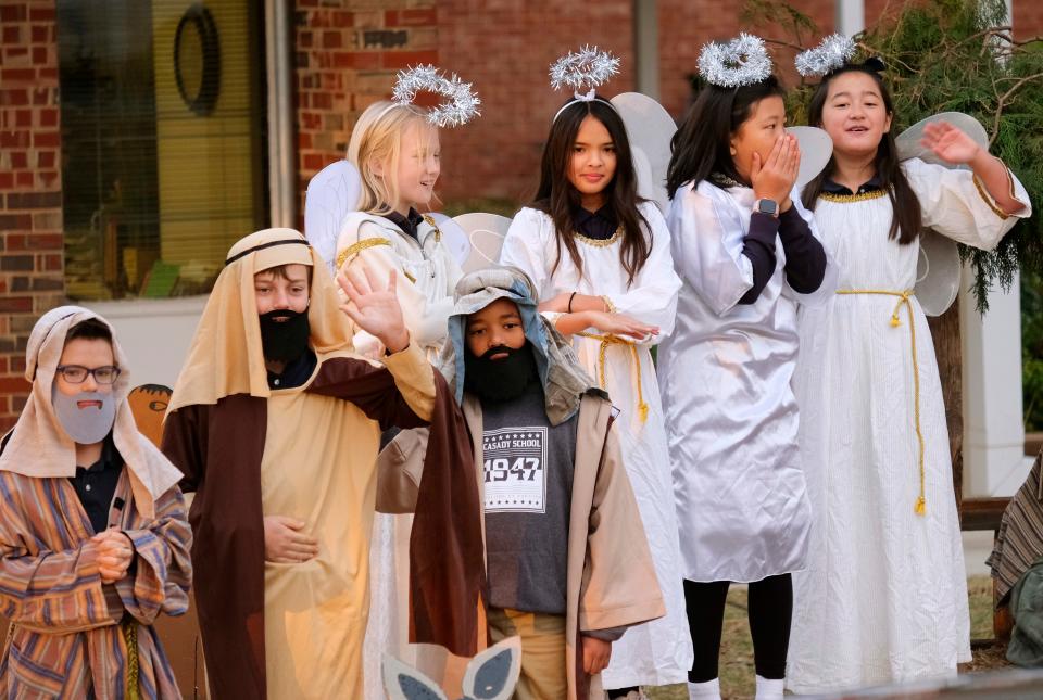 Students dressed as angels and shepherds react to the car line. Fourth-grade students at Casady's Lower Division dressed as biblical characters, creating a live nativity scene performed at the circle drive as students were dropped off for school.