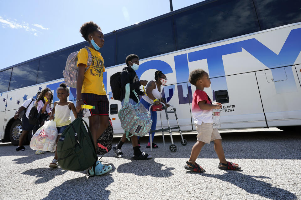 Evacuees walk to board buses Tuesday, Aug. 25, 2020, in Galveston, Texas. The evacuees are being taken to Austin, Texas, as Hurricane Laura heads toward the Gulf Coast. (AP Photo/David J. Phillip)