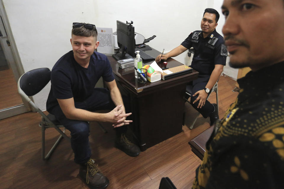 Bodhi Mani Risby-Jones from Queensland, Australia, left, sits at the local immigration office as his lawyer Idris Marbawi, right, looks on, in Meulaboh, Aceh, Indonesia on Wednesday, June 7, 2023. The Australian surfer who was jailed for attacking several people while drunk and naked in Indonesia's deeply conservative Muslim province of Aceh will be deported back to his country after he agreed to apologize and pay compensation, officials said Wednesday. (AP Photo/Sultan Ikbal Abiyyu)