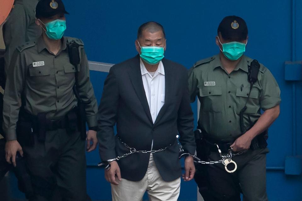 Jimmy Lai, who founded the now-shuttered Apple Daily, is escorted by Correctional Services officers to a prison van before appearing in a court in Hong Kong on 12 December 2020 (AP)