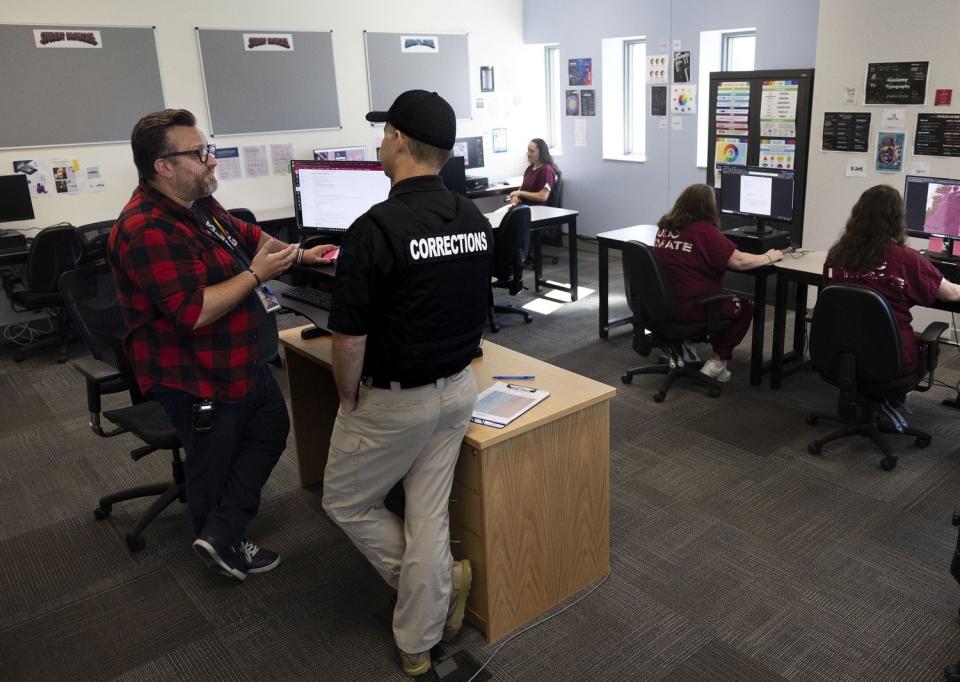 Davis Technical College instructor Blake Heywood speaks with a corrections officer in the web and graphic design classroom at the Utah State Correctional Facility in Salt Lake City on Friday.