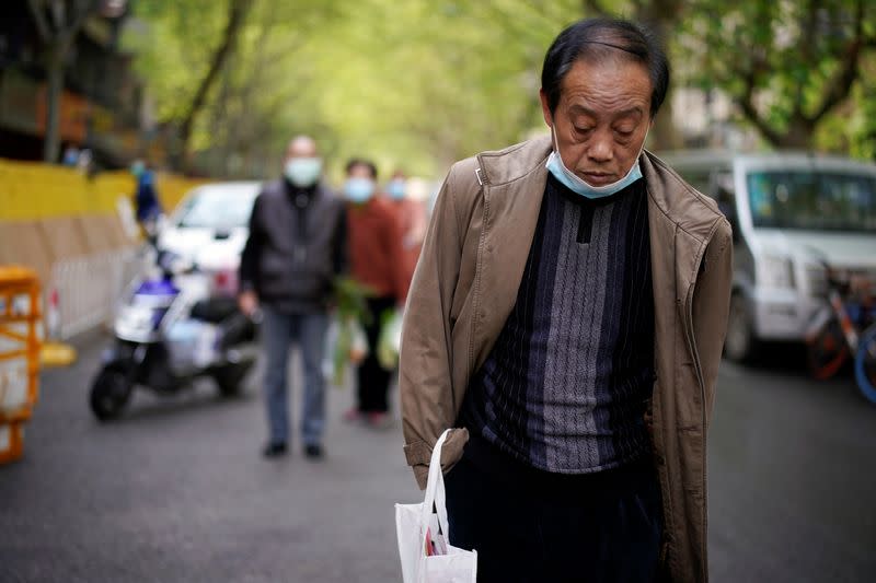 Man with a face mask observes a moment of silence on a street in Wuhan