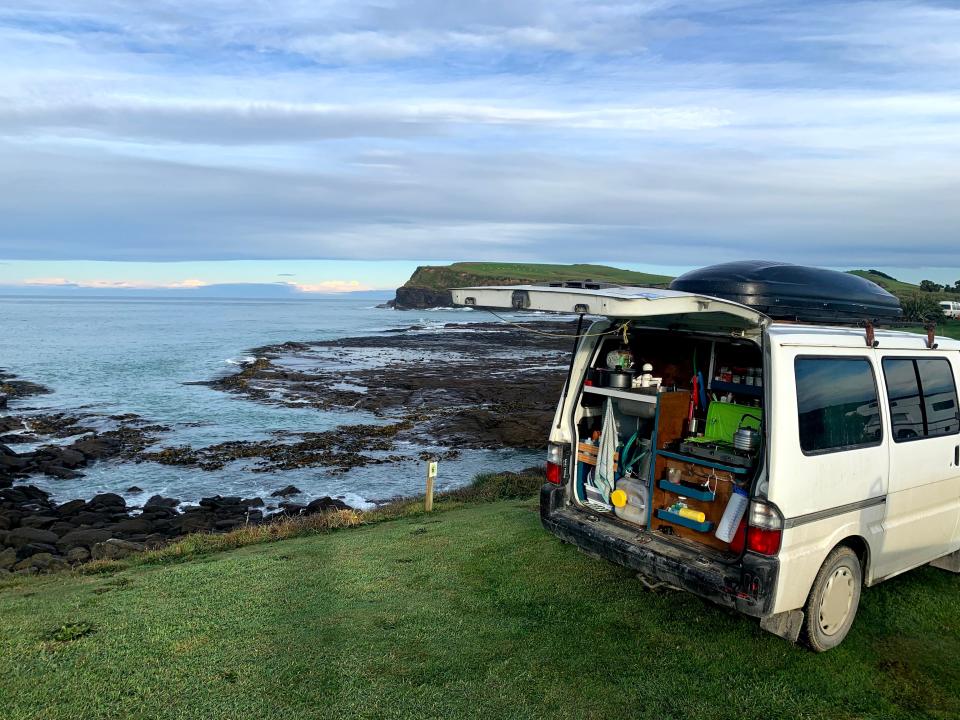 a van with an open trunkn parked in front of a body of water