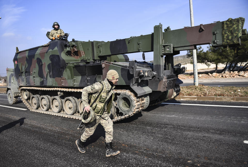 Turkish troops and artillery prepare to enter Syria, in Reyhanli, Hatay, Turkey, Friday, Feb. 14, 2020. A Syrian military official and activists say a government helicopter has been shot down in the country's northwest where a military offensive against opposition fighters is unfolding. Videos posted online show a helicopter spiraling downward from the sky, with flames trailing behind as onlookers cheer. (AP Photo)