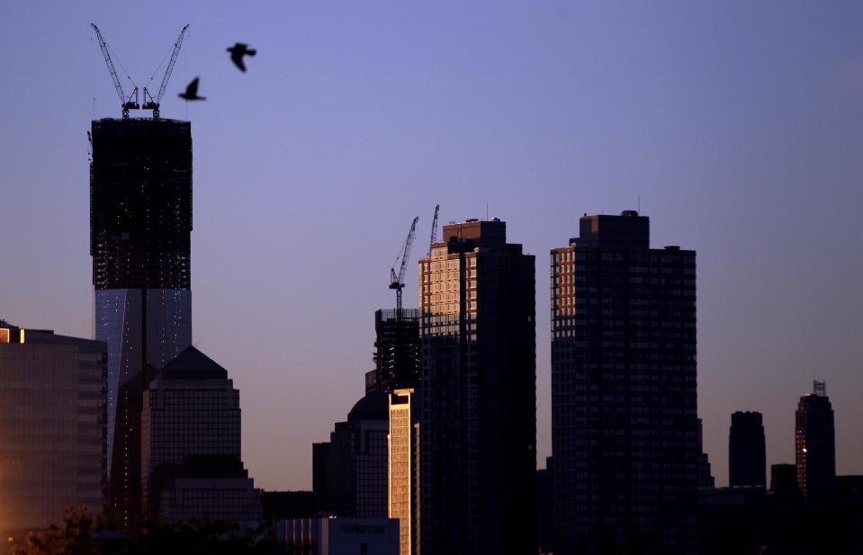 Viewed from Jersey City, N.J., two birds fly by as the sun rises over buildingsin New York, including One World Trade Center, tallest building at left, Monday, April 30, 2012. One World Trade Center, the giant monolith being built to replace the twin towers destroyed in the Sept. 11 attacks, will lay claim to the title of New York City's tallest skyscraper on Monday. (AP Photo/Julio Cortez)