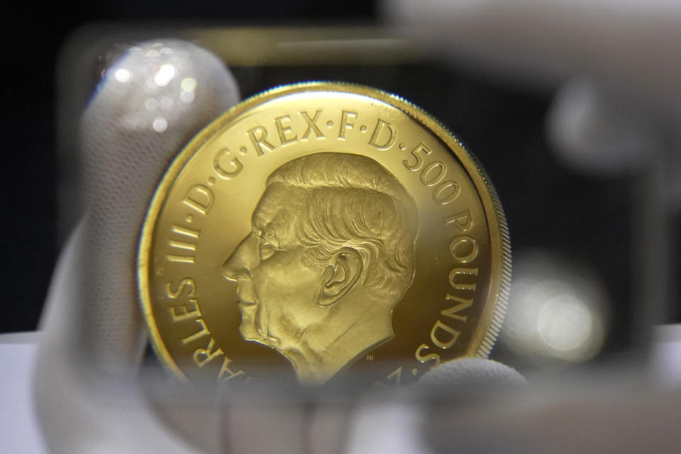 A coin featuring the portrait of King Charles III, is assessed during the "Trial of the Pyx,'' a ceremony that dates to the 12th Century in which coins are weighed in order to make certain they are up to standard, at the Goldsmiths' Hall in London, Tuesday, Feb. 7, 2023. A jury sat solemnly in a gilded hall in central London on Tuesday, presided over by a bewigged representative of the crown in flowing black robes, but there were no criminals in the dock. (AP Photo/Kin Cheung)