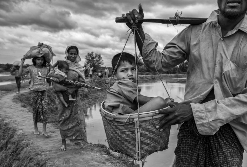 A Rohingya refugee boy is carried in a basket by a relative on Sept. 24 after crossing the border on the Bangladesh side of the Naf River while fleeing Myanmar. (Photo: Kevin Frayer via Getty Images)