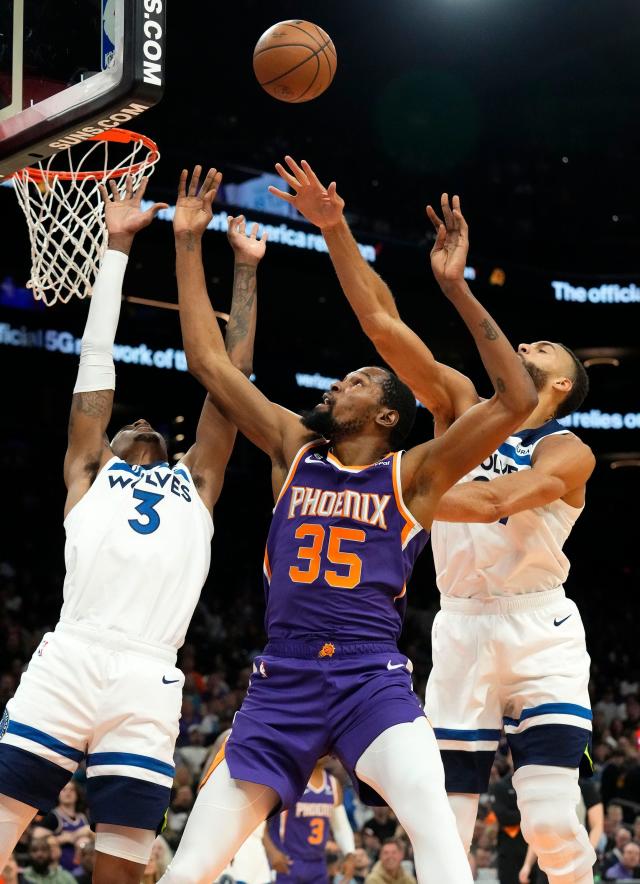 Phoenix Suns forward Kevin Durant (35) takes a shot against Minnesota Timberwolves forward Jaden McDaniels (3) and center Rudy Gobert (27) in the first half at Footprint Center.