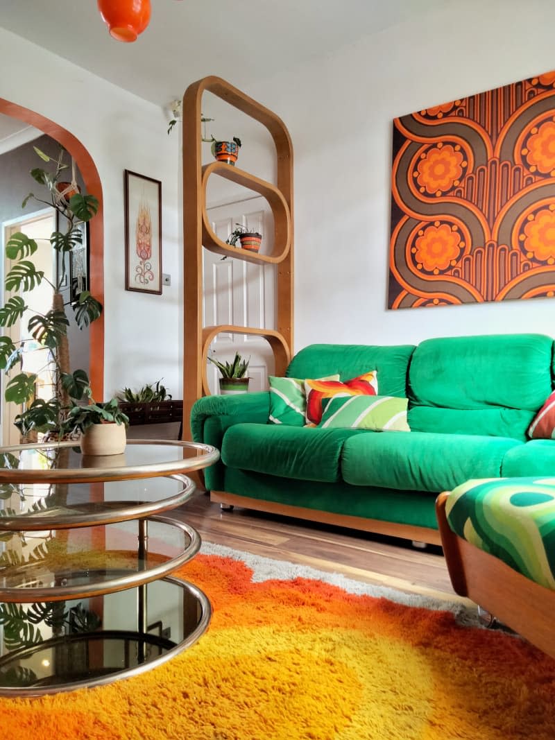 Colorful decorated living room with orange accents and green fabric couch.