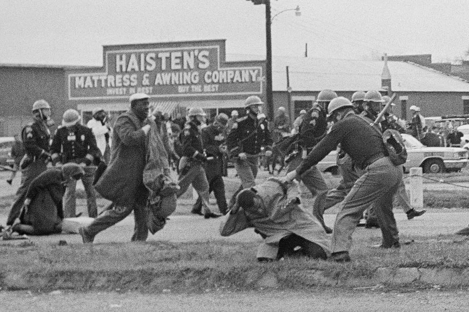 FILE - In this March 7, 1965, file photo, a state trooper swings a billy club at John Lewis, right foreground, chairman of the Student Nonviolent Coordinating Committee, to break up a civil rights voting march in Selma, Ala. Lewis sustained a fractured skull. Lewis, who carried the struggle against racial discrimination from Southern battlegrounds of the 1960s to the halls of Congress, died Friday, July 17, 2020. (AP Photo/File)