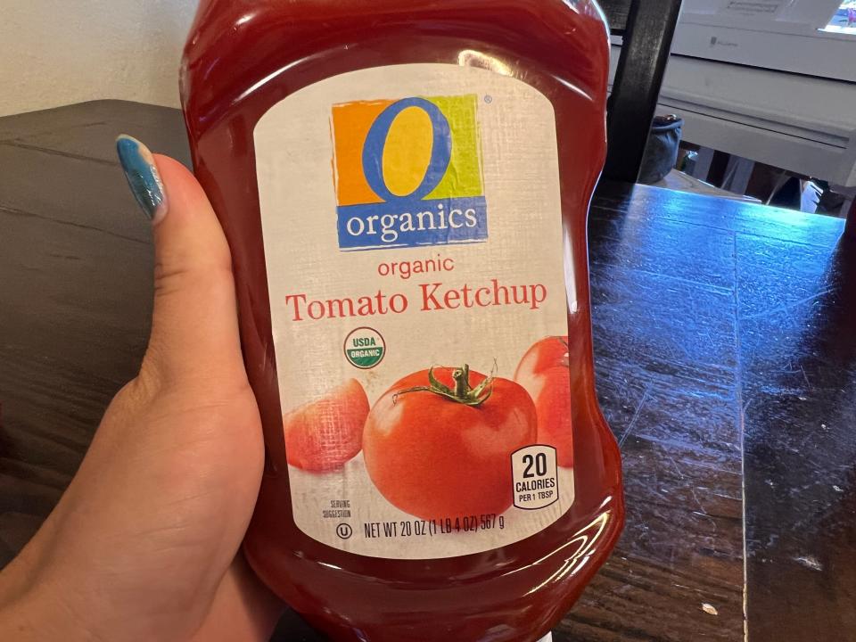 Hand holding a bottle of the Organics brand ketchup