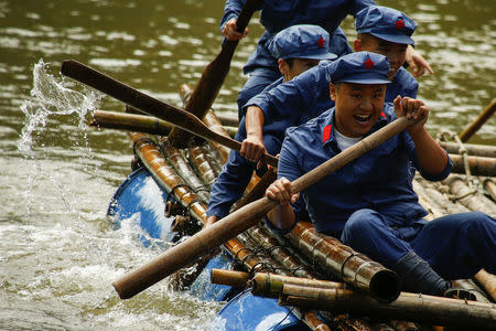 Participants dressed in replica red army uniforms paddle as they race on a raft across a lake during a Communist team-building course extolling the spirit of the Long March, organised by the Revolutionary Tradition College, in the mountains outside Jinggangshan, Jiangxi province, China, September 14, 2017. REUTERS/Thomas Peter