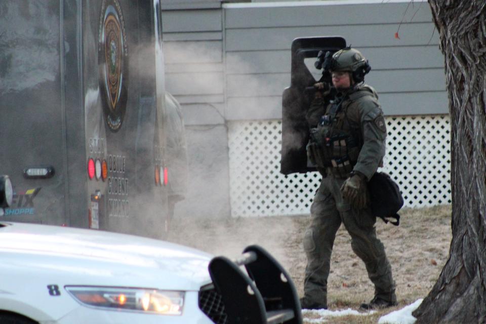 A Great Falls police officer approaches the department's Mobile Incident Command vehicle carrying a ballistic shield during Monday morning's standoff.