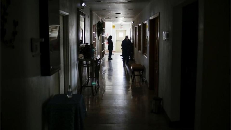 Personas en un corredor de un edificio sin luz