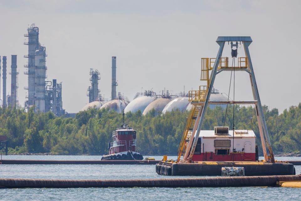 An oil and gas refinery rises in the background not far from where the U.S. Army Corps of Engineers is building an underwater sill in the Mississippi River that they hope will keep saltwater from moving farther up the Mississippi River south of New Orleans, Tuesday, Sept. 26, 2023.