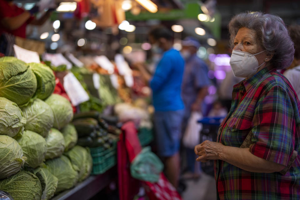 A customer wearing a face mask waits to buy vegetables at the Maravillas market in Madrid, Thursday, May 12, 2022. Russia's war in Ukraine has accelerated inflation across Europe, with prices for energy, materials and food surging at rates not seen for decades. Inflation is expected to hit nearly 7% this year in the 27-nation EU and is contributing to slowing growth forecasts. (AP Photo/Manu Fernandez)