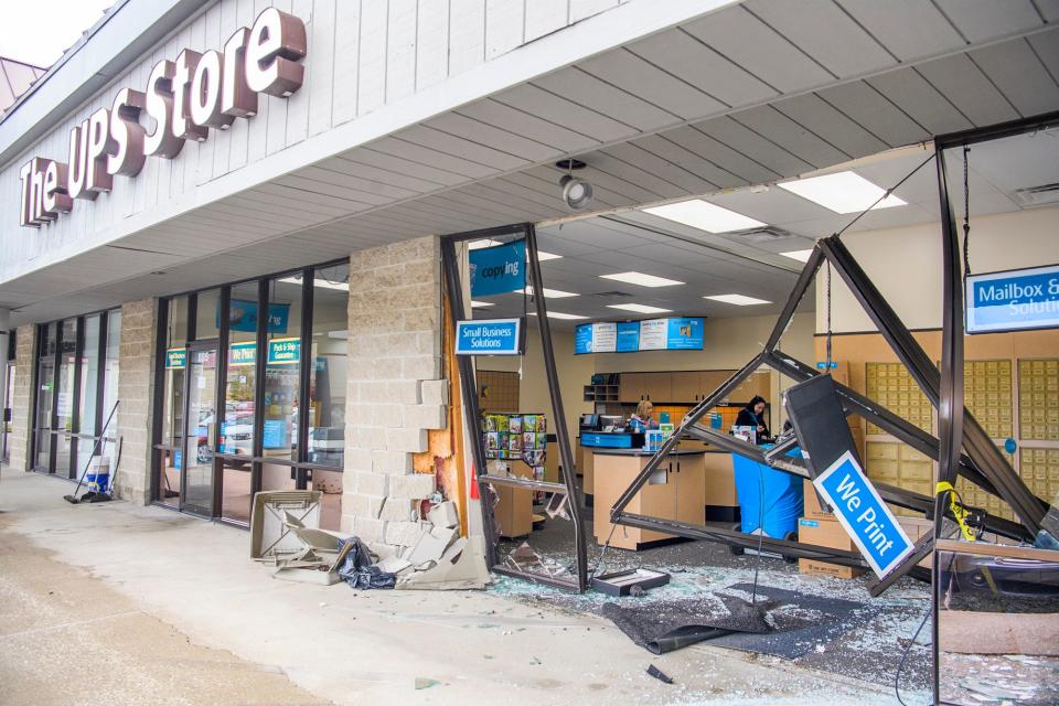 UPS Store employees are seen working after a vehicle destroyed the storefront late Friday morning at The Shoppes on Bloomington's east side.