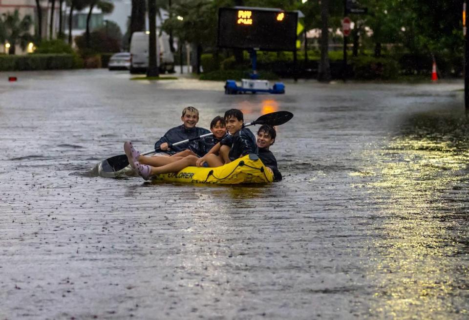 Matthew Koziol, de 16 años, Matías Ricci, de 13, Manuel Ricci, de 17, y Raúl Fernández, de 16, viajan en canoa por una calle inundada por las fuertes lluvias en North Bay Rd en Sunny Isles Beach el miércoles 12 de junio de 2024 en Florida.