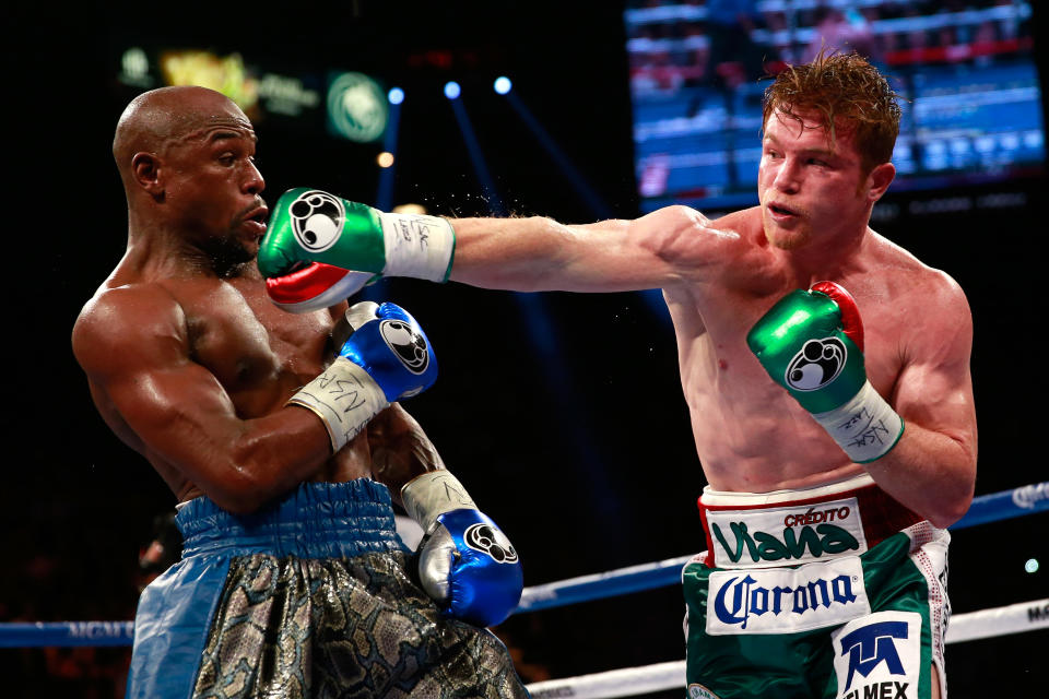 LAS VEGAS, NV - 14 DE SEPTIEMBRE: (RL) Canelo Alvarez lanza un derechazo a Floyd Mayweather Jr. durante su pelea por el título de 154 libras WBC/WBA en el MGM Grand Garden Arena el 14 de septiembre de 2013 en Las Vegas, Nevada.  (Foto de Chris Trotman/Golden Boy/Golden Boy a través de Getty Images)