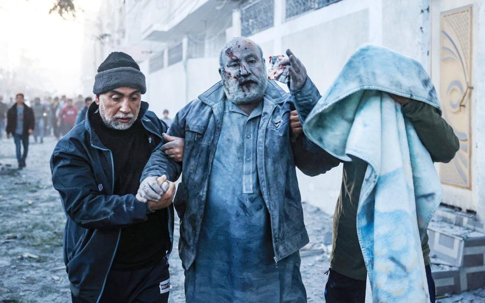 Palestinians help a man injured in an Israeli strike in Rafah