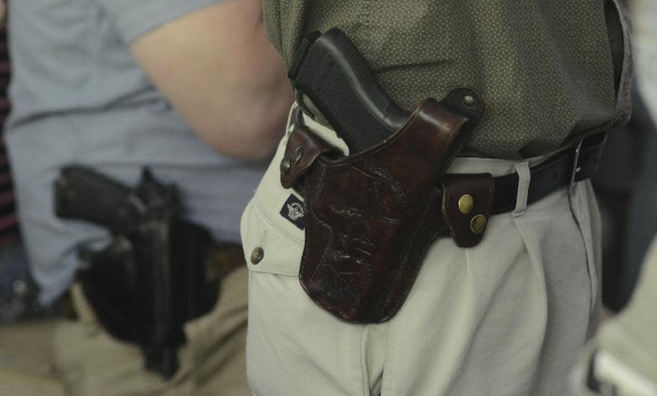 Jeff Anderson (derecha), del Condado Pickens, fue uno de los muchos asistentes que llevaron sus pistolas a la ceremonia de firma de una ley por el gobernador de Georgia, Nathan Deal, a Ellijay, Georgia. (Foto AP/Chattanooga Times Free Press, John Rawlston)